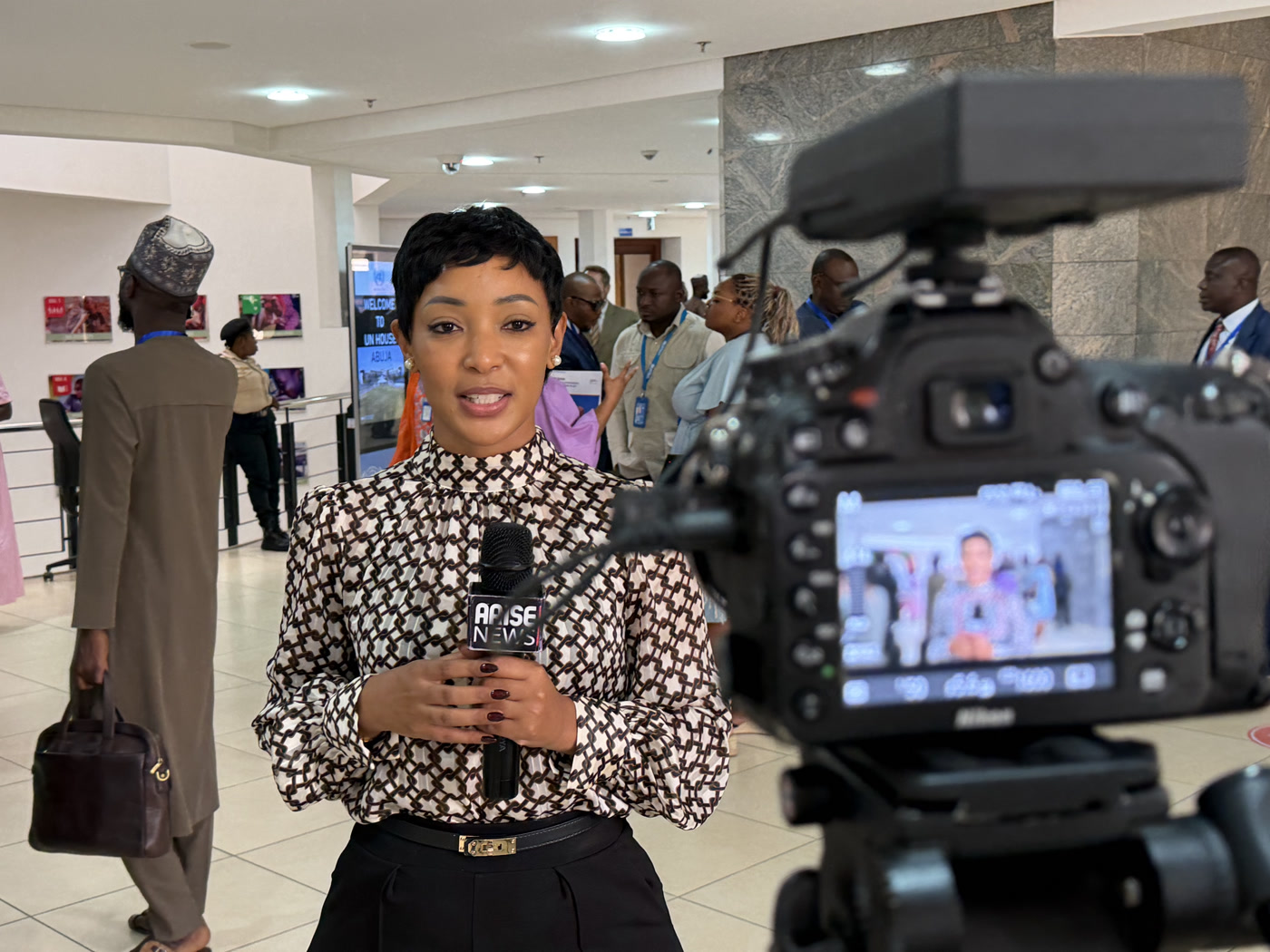 Yolanda Robert reporting on camera with an Arise News microphone at UN House, Abuja